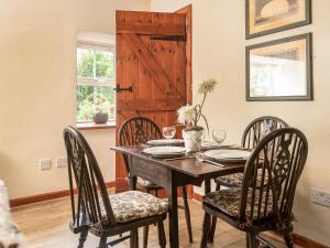 ein Esszimmer mit einem Tisch mit Stühlen und einer Holztür in der Unterkunft Broomstick Cottage in Elsdon