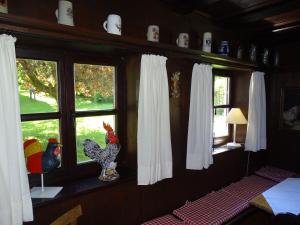 Cette chambre est dotée de fenêtres avec des rideaux blancs et une statue de poulet. dans l'établissement Haus Victoria, à Schöllnach