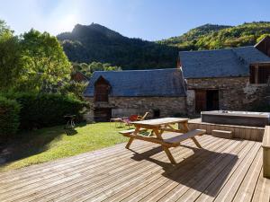 eine Holzterrasse mit einem Picknicktisch darüber in der Unterkunft Maison de village rénovée pour 12 pers avec jardin et jacuzzi proche Loudenvielle - FR-1-695-89 in Adervielle
