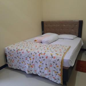a bed with a bedspread with flowers on it at De Adisucipto Homestay Syariah 2 in Ngadipuro