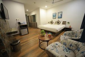 ein Schlafzimmer mit einem Bett, einer Couch und einem Tisch in der Unterkunft Hillside Aqua in Bhubaneshwar