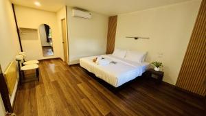 a bedroom with a large white bed and wooden floors at Cha homestay in Phanom