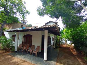 米瑞莎Mirissa Gallivant Resort的一栋白色的小房子，门廊上摆放着椅子