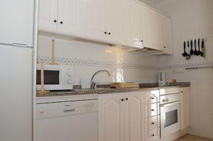 eine Küche mit weißen Schränken und einer weißen Mikrowelle in der Unterkunft Ferienhaus für 6 Personen ca 88 m in Estrella de Mar, Murcia Costa Calida in Los Urrutias
