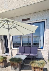 a white umbrella and two purple chairs and a table at Studio Zeezicht in Vlissingen
