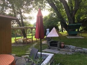 um guarda-chuva vermelho e uma grelha em um quintal em Ferienhaus In Steindorf Am Ossiacher See em Steindorf am Ossiacher See