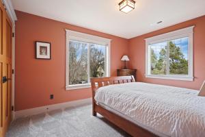 Schlafzimmer mit orangefarbenen Wänden, einem Bett und zwei Fenstern in der Unterkunft Awbrey in Bend