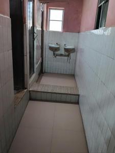 an empty bathroom with two sinks and a window at V R S Dormitory in Hubli