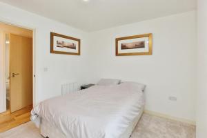 ein Schlafzimmer mit einem weißen Bett und zwei Bildern an der Wand in der Unterkunft Executive apartment in central Milton Keynes in Milton Keynes