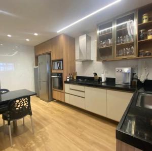 a kitchen with stainless steel appliances and wooden cabinets at Carnatal Agora- 30m da Arena das Dunnas in Natal
