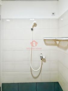 Jombang-kulonにあるStrategic Akasa 1BR Apt BSD W Pool & Gymの白いタイル張りの壁にホース付きのシャワーが備わります。