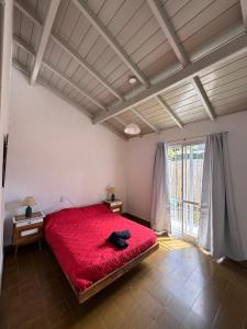 une chambre avec un lit rouge et une grande fenêtre dans l'établissement Casa DorisHouse, à Necochea