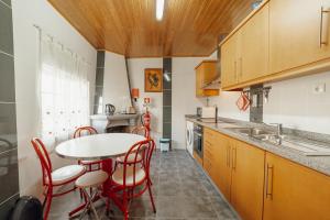 une cuisine avec une table et des chaises rouges dans une pièce dans l'établissement Casa do Malhadinhas - Vacationy, à Vila Nova de Paiva