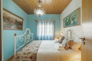 - une chambre avec un lit aux murs bleus et un lustre dans l'établissement Casa do Malhadinhas - Vacationy, à Vila Nova de Paiva