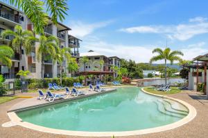 una piscina con tumbonas y palmeras en Laguna Edge - Tranquil Poolside Escape by the Sea, en Trinity Beach