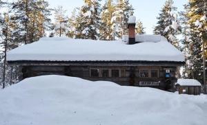 une maison recouverte de neige avec un tas de neige dans l'établissement Kelosix, à Vuostimo