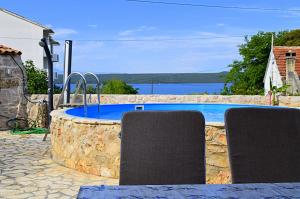 a pool with two chairs and a table with a view of the water at Ferienhaus In Dobropoljana Mit Privatem Pool in Dobropoljana