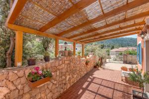 a patio with a stone wall and a wooden pergola at Appartement Casper Mit Terrasse, Garten Und Grill in Veli Lošinj