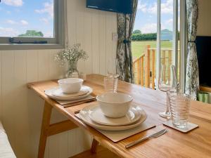 a wooden table with two bowls and wine glasses at The Coop in Broadway