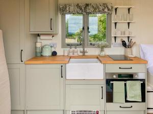 a kitchen with white cabinets and a sink and a window at The Coop in Broadway