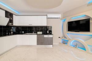 a kitchen with white cabinets and a flat screen tv at Rua Luxury Villa in Alykes