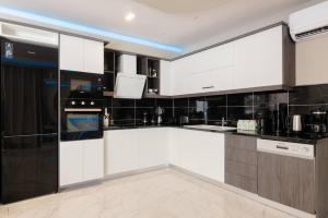 a kitchen with white cabinets and black appliances at Rua Luxury Villa in Alykes