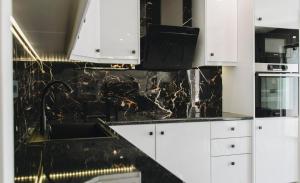 a kitchen with white cabinets and a black counter top at Mat Luxury Villa in Zakynthos +33 photos