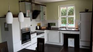 une cuisine avec des armoires blanches, un évier et une fenêtre dans l'établissement Ferienhaus Tante Waltraut In Garz Auf Usedom, à Garz