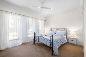 a white bedroom with a bed and two windows at Sea La Vie in Arakoon