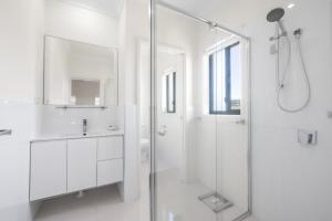 a white bathroom with a shower and a sink at Sea La Vie in Arakoon +16 photos