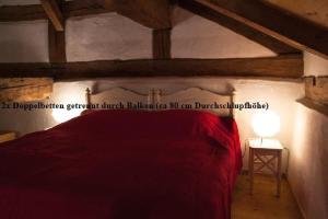 ein Schlafzimmer mit einem roten Bett und einer Lampe in der Unterkunft Einzimmer-Wohnung mit Galerie für vier Personen in Schernfeld
