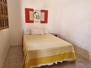 ein kleines Schlafzimmer mit einem Bett mit einer gelben Decke in der Unterkunft Casa de Veraneio com 4 quartos in Barra de São Miguel