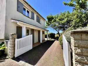 une clôture blanche devant une maison dans l'établissement Maison 4 pièces La Brée-les-Bains - Proche Plage - FR-1-246A-318, à La Brée-les-Bains