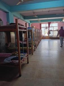 a row of bunk beds in a room with a person walking at V R S Dormitory in Hubli