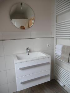 a white bathroom with a sink and a mirror at Große Wohnung In Diekmannshausen in Süderschweiburg