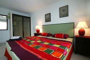 a bedroom with a large colorful bed with two lamps at Casa Romeo Mit Kaminofen Und Sonnenterrasse in Guía de Isora