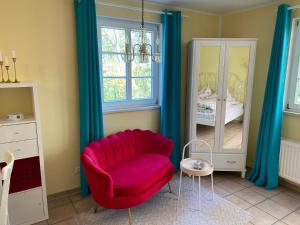 un salon avec une chaise rouge et un miroir dans l'établissement Großzügiges Studio In Einem Kleinen Fachwerkhaus, à Dömitz