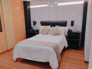 una habitación con una cama grande con sábanas y almohadas blancas en Hotel Veler, en Medellín