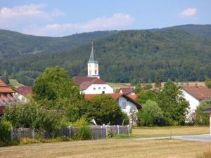 une église blanche avec une cloche dans un village dans l'établissement Ferienwohnung Simon In Gleißenberg, à Gleißenberg
