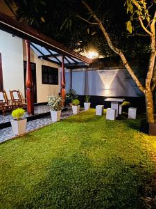 a garden with a table and chairs and a tree at Villa Happy Nest in Unawatuna