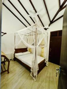 a bedroom with a bed with mosquito net at Villa Happy Nest in Unawatuna