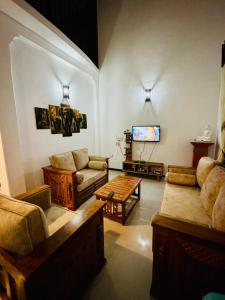 a living room with a couch and a tv at Villa Happy Nest in Unawatuna