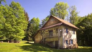 an old building with a balcony on a green field at Gozdna koča Studeno in Kočevje