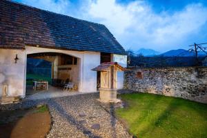 - un vieux bâtiment en pierre avec une table et des chaises à l'extérieur dans l'établissement Curte la Munte - charming village house, à Sebeşu de Sus