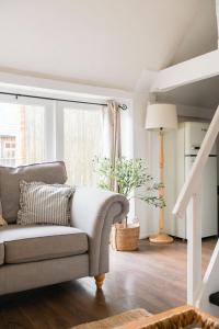 un salon avec un canapé et une fenêtre dans l'établissement The Dairy Cotswolds Cottage Farm With Pool, à Lechlade