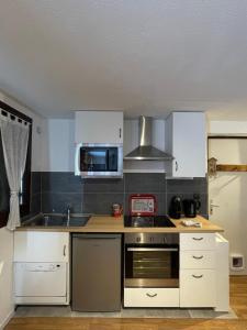 a kitchen with white cabinets and a stove top oven at Le refuge du Cerf in Allemont