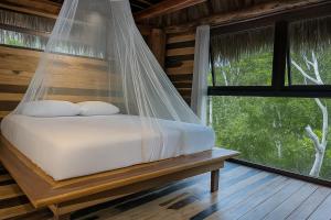 a bed in a room with a mosquito net at Treehouse Tulum H2Ojos in Tulum