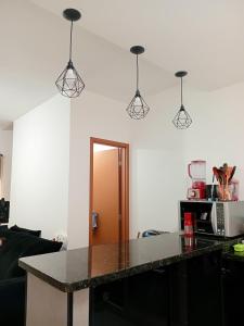 a kitchen with a counter top and four lights at Bem praiana in Praia Grande