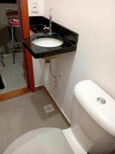 a bathroom with a white toilet and a sink at Bem praiana in Praia Grande