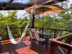 a patio with a table and chairs and an umbrella at Treehouse Tulum H2Ojos in Tulum
